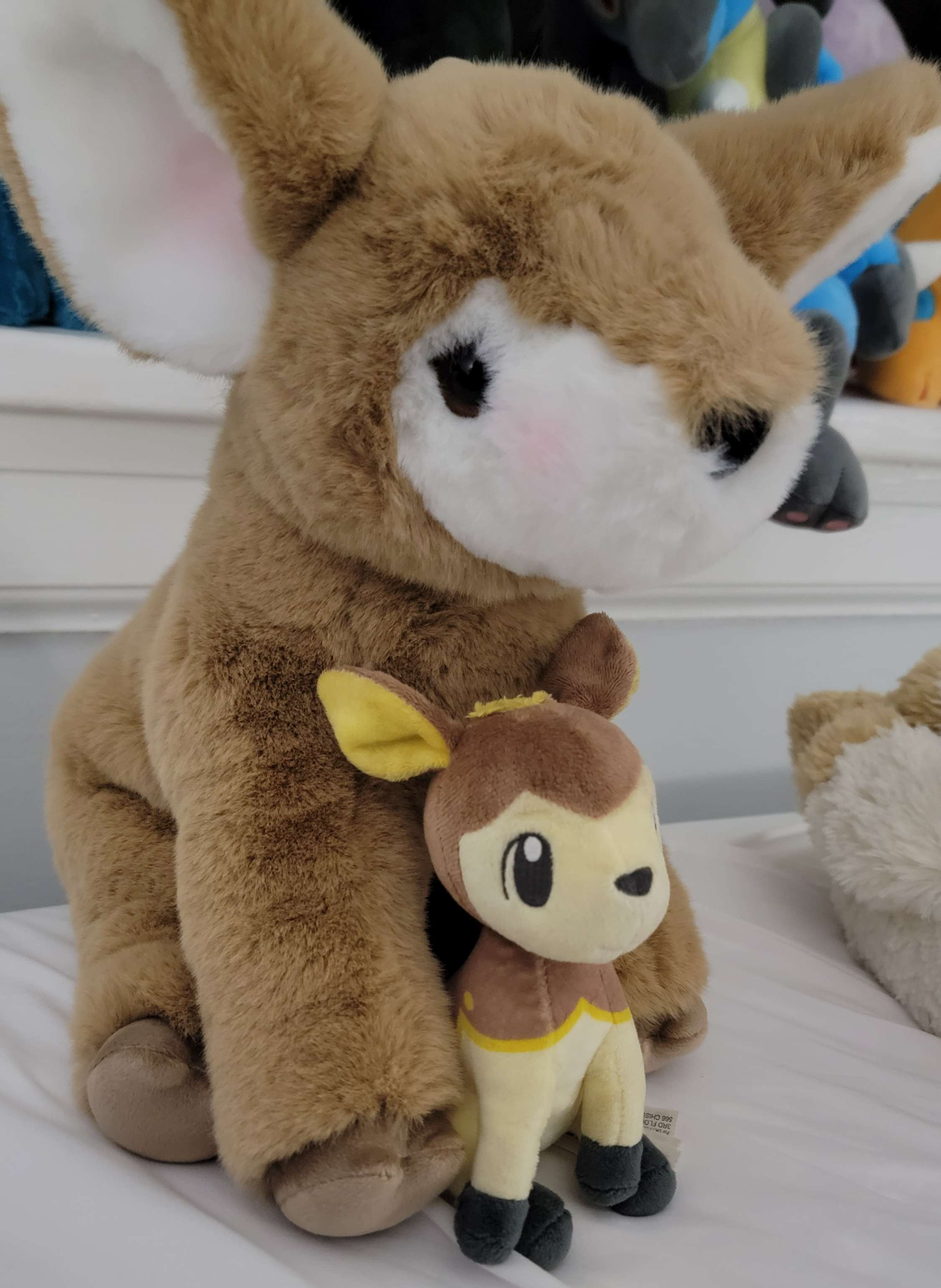 Pumpkin sits with a small plush Deerling Pokemon in between her two legs.